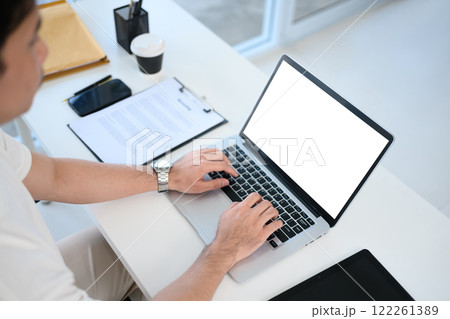 Close up view of young entrepreneur working on laptop in a modern office 122261389