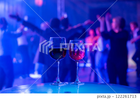 Two wine glasses in vibrant nightlife party scene 122261713