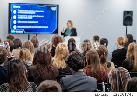 Audience listening to presentation at business conference with speaker and screen display 122261740