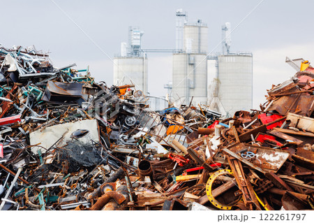 Scenic metal scrap yard huge pile of rusty metal parts disposal waste at junkyard recycling site against industrial factory plant area at Germany. Scrapyard waste management industry background 122261797