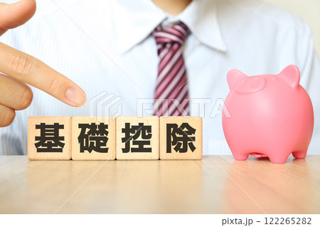 基礎控除のイメージ ビジネスマンの男性と豚の貯金箱 基礎控除のイメージ ビジネスマンの男性と豚の貯金箱 122265282