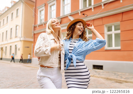 Happy women walk along city streets on sunny day. Young girlfriends having fun outdoors. Lifestyle. Happy women walk along city streets on sunny day. Young girlfriends having fun outdoors. Lifestyle. 122265816