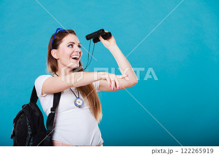 Tourist woman looking through binoculars on blue Tourist woman looking through binoculars on blue 122265919