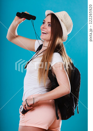 Tourist woman looking through binoculars on blue Tourist woman looking through binoculars on blue 122265920