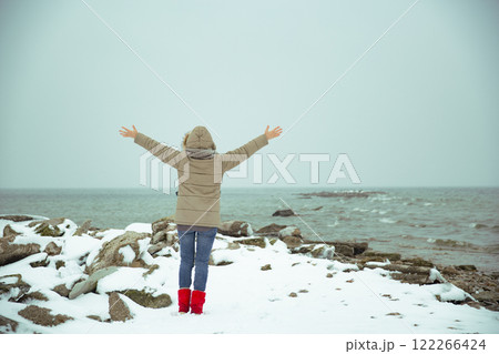 Woman on the shore of a snowy sea. Foggy winter Woman on the shore of a snowy sea. Foggy winter 122266424