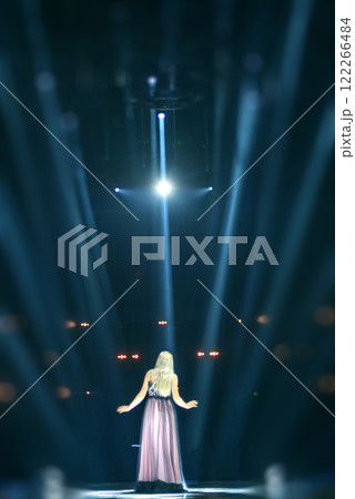 an artist sings into a microphone on stage at a concert 122266484