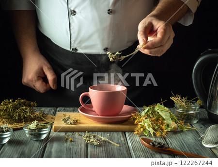 Herbalist prepares fragrant tea on the kitchen table. Using her hands, add motherwort to a pink mug of boiling water to make a soothing tea. Traditional medicine concept or making a medicinal tea 122267244