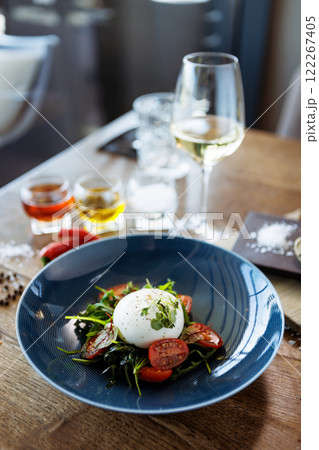 Burrata with paprika-truffle jam and cherry-cluster tomato salad. Delicious healthy Italian traditional food closeup served for lunch in modern gourmet cuisine restaurant Burrata with paprika-truffle jam and cherry-cluster tomato salad. Delicious healthy Italian traditional food closeup served for lunch in modern gourmet cuisine restaurant 122267405