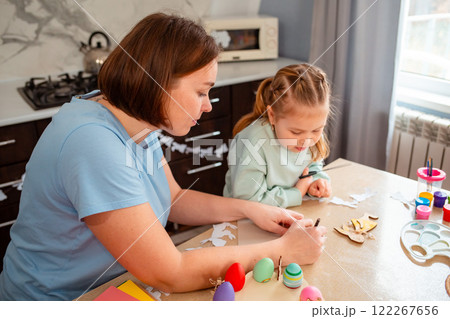 Mid shot of young Caucasian mother and her little daughter carve rabbits out of paper to create decorations for the house. Spring Easter holiday with the family 122267656