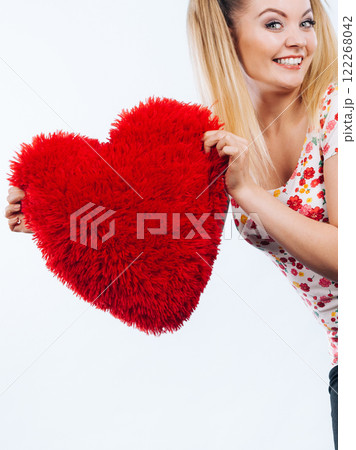 Happy woman holding heart shaped pillow Happy woman holding heart shaped pillow 122268042