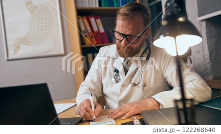 Focused on medical, doctor in medical advice, glasses, and stethoscope, sitting at table in his office and prescription treatment 122268640