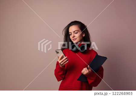 Happy woman wearing red sweater and headphones enjoying listening music on pink background. Happy woman wearing red sweater and headphones enjoying listening music on pink background. 122268903