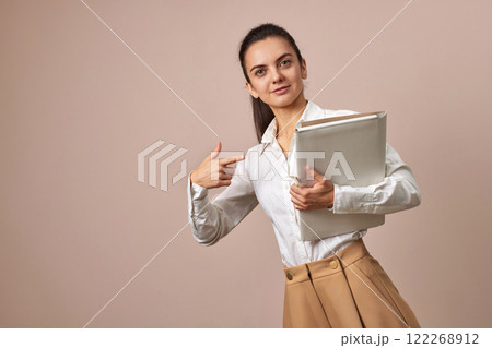 happy businesswoman holding folders. Confident woman in white shirt pointing at folders, copy space happy businesswoman holding folders. Confident woman in white shirt pointing at folders, copy space 122268912