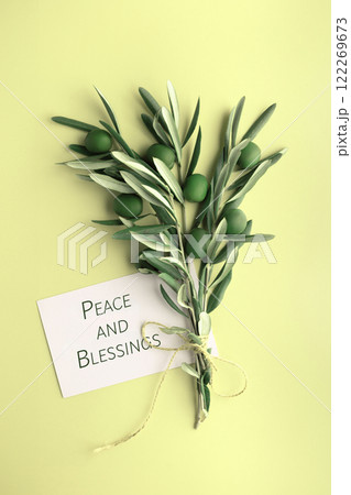 Olive branch with green olives and blank card on light yellow background. Peace and blessings Olive branch with green olives and blank card on light yellow background. Peace and blessings 122269673