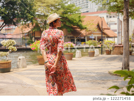 Young woman in ethnic dress and hat exploring the vibrant streets of Malacca, Malaysia. A blend of cultural heritage, colorful architecture, and tropical charm. Perfect travel and lifestyle moments. 122271458