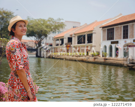 Young woman in ethnic dress and hat exploring the vibrant streets of Malacca, Malaysia. A blend of cultural heritage, colorful architecture, and tropical charm. Perfect travel and lifestyle moments. 122271459