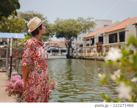 Young woman in ethnic dress and hat exploring the vibrant streets of Malacca, Malaysia. A blend of cultural heritage, colorful architecture, and tropical charm. Perfect travel and lifestyle moments. Young woman in ethnic dress and hat exploring the vibrant streets of Malacca, Malaysia. A blend of cultural heritage, colorful architecture, and tropical charm. Perfect travel and lifestyle moments. 122271460