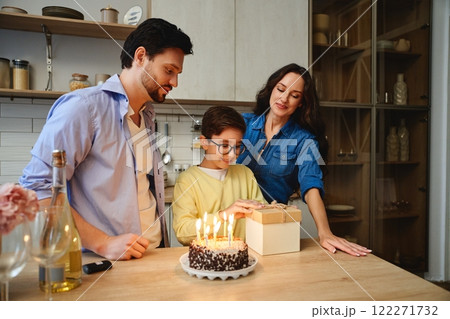 Family celebrates a young boys birthday with cake and gifts at home 122271732