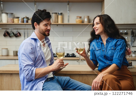 A couple enjoys wine and conversation in a modern kitchen setting A couple enjoys wine and conversation in a modern kitchen setting 122271746