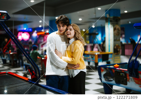 Young couple enjoys a playful moment at an arcade during evening hours Young couple enjoys a playful moment at an arcade during evening hours 122271809