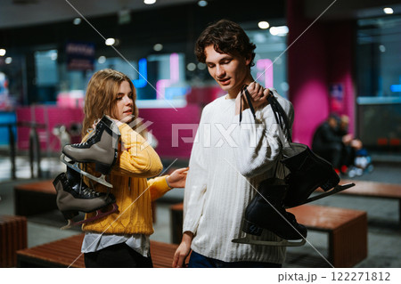 Friends carrying ice skates while enjoying an evening at an ice rink Friends carrying ice skates while enjoying an evening at an ice rink 122271812