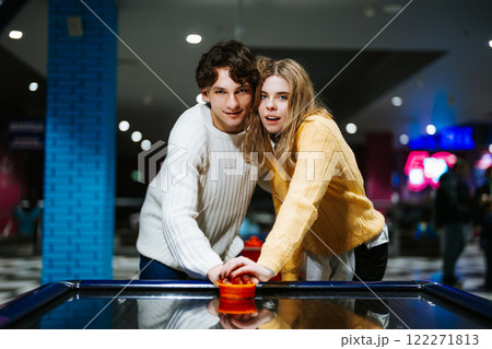 Young couple enjoys air hockey at a vibrant arcade in evening Young couple enjoys air hockey at a vibrant arcade in evening 122271813