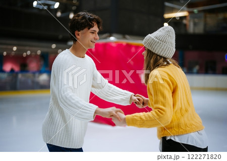 Young couple enjoying ice skating together in a rink during winter 122271820