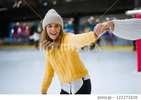 Enjoying ice skating at a winter rink in a cozy yellow sweater 122271826