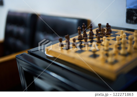 Chess game in progress on a wooden board in a quiet lounge area 122271863
