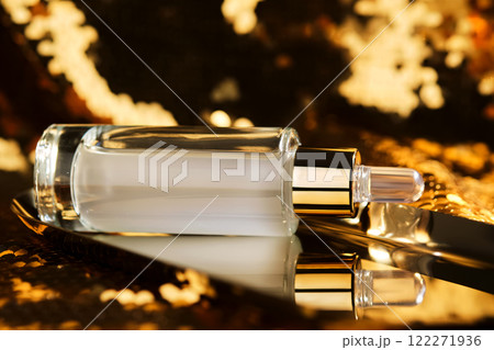 A bottle of cosmetic serum with a pipette on a festive golden background. A bottle of cosmetic serum with a pipette on a festive golden background. 122271936