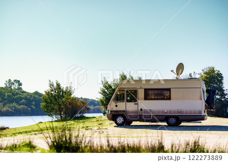Caravan camping on lake shore with satellite dish on roof 122273889