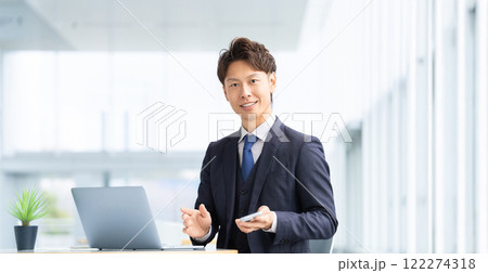 パソコンとスマートフォンを使う爽やかな笑顔の男性ビジネスマン 122274318