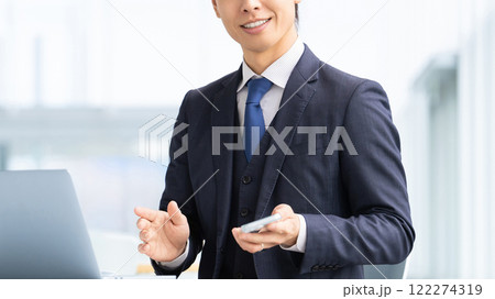 パソコンとスマートフォンを使う爽やかな笑顔の男性ビジネスマン パソコンとスマートフォンを使う爽やかな笑顔の男性ビジネスマン 122274319