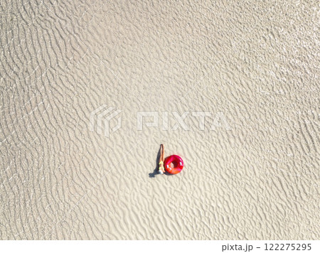 Aerial view of lying slim woman with swimming ring, sandy beach 122275295