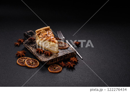 Delicious fresh cheesecake caramel peanut cake with cream and nuts on a ceramic plate on a dark concrete background 122276434