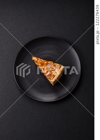 Delicious fresh cheesecake caramel peanut cake with cream and nuts on a ceramic plate on a dark concrete background Delicious fresh cheesecake caramel peanut cake with cream and nuts on a ceramic plate on a dark concrete background 122276439