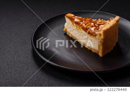 Delicious fresh cheesecake caramel peanut cake with cream and nuts on a ceramic plate on a dark concrete background Delicious fresh cheesecake caramel peanut cake with cream and nuts on a ceramic plate on a dark concrete background 122276440