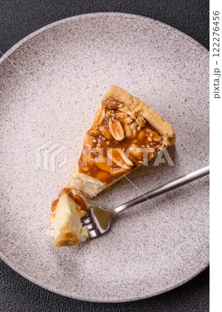 Delicious fresh cheesecake caramel peanut cake with cream and nuts on a ceramic plate on a dark concrete background Delicious fresh cheesecake caramel peanut cake with cream and nuts on a ceramic plate on a dark concrete background 122276456