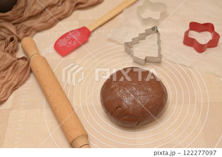 Christmas homemade baking, brown cocoa dough for baking gingerbread, shaped cutter, silicone spatula and rolling pin on the table Christmas homemade baking, brown cocoa dough for baking gingerbread, shaped cutter, silicone spatula and rolling pin on the table 122277097