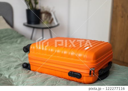 Big orange suitcase on the bed in light room. Baggage case packing getting ready to travel trip vacation. Lifestyle, adventure and tourism concept. 122277116