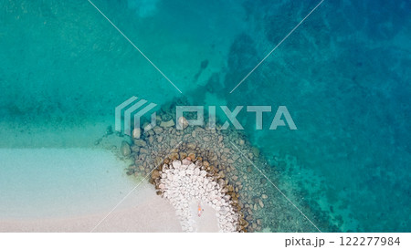 A stunning aerial shot of turquoise sea water and man lying on soft sandy beach. Tropical paradise A stunning aerial shot of turquoise sea water and man lying on soft sandy beach. Tropical paradise 122277984