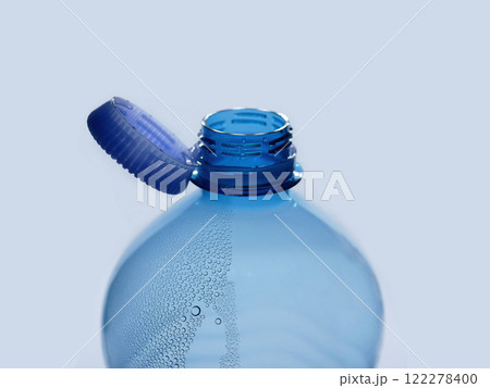 A new mechanism of plastic bottle with a stationary fixed tethered cap. Blue plastic PET water bottle with cup open close up isolated on white. Recycling, environment friendly and ecology concept 122278400