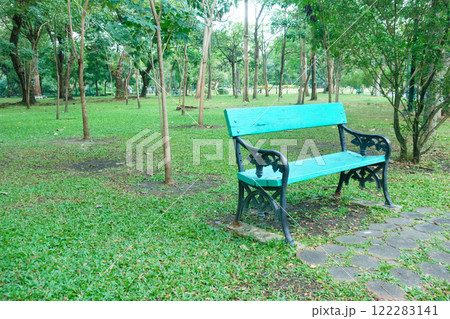 vibrant blue bench sits in lush green park surrounded by trees, inviting relaxation and tranquility. serene atmosphere enhances beauty of nature 122283141
