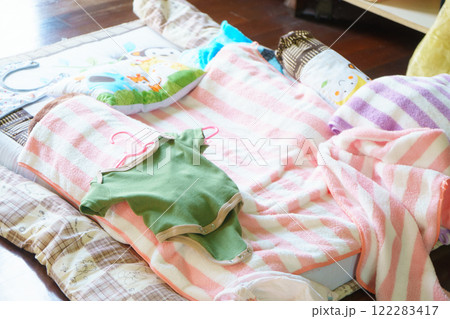 Cozy baby bedding with colorful blankets and clothes on soft surface. scene evokes warmth and comfort, perfect for nursery or play area Cozy baby bedding with colorful blankets and clothes on soft surface. scene evokes warmth and comfort, perfect for nursery or play area 122283417