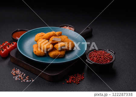 Delicious fresh crispy chicken nuggets on a dark concrete background Delicious fresh crispy chicken nuggets on a dark concrete background 122287338