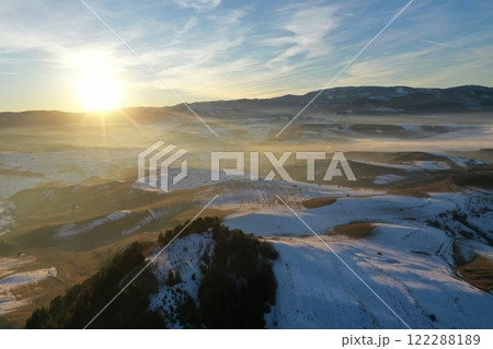 Aerial view of sunset over misty winter mountains Aerial view of sunset over misty winter mountains 122288189
