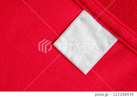 Blank white laundry care clothes label on red shirt fabric texture background Blank white laundry care clothes label on red shirt fabric texture background 122288439