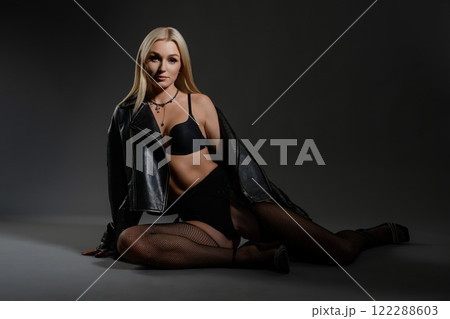 Stylish model in lingerie poses confidently with leather jacket in studio 122288603