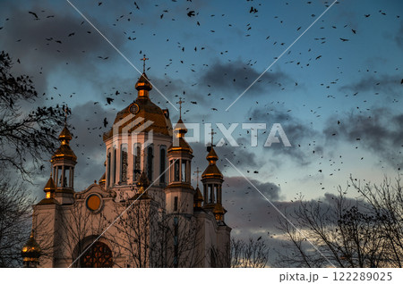 Church with crows. Flock of crows is circling around a church.. Church with silhouettes of crows in the dark evening sky. Church with crows. Flock of crows is circling around a church.. Church with silhouettes of crows in the dark evening sky. 122289025