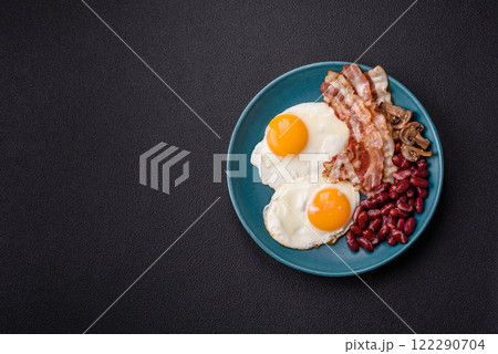 English breakfast with fried eggs, bacon, beans, tomatoes, spices and herbs 122290704